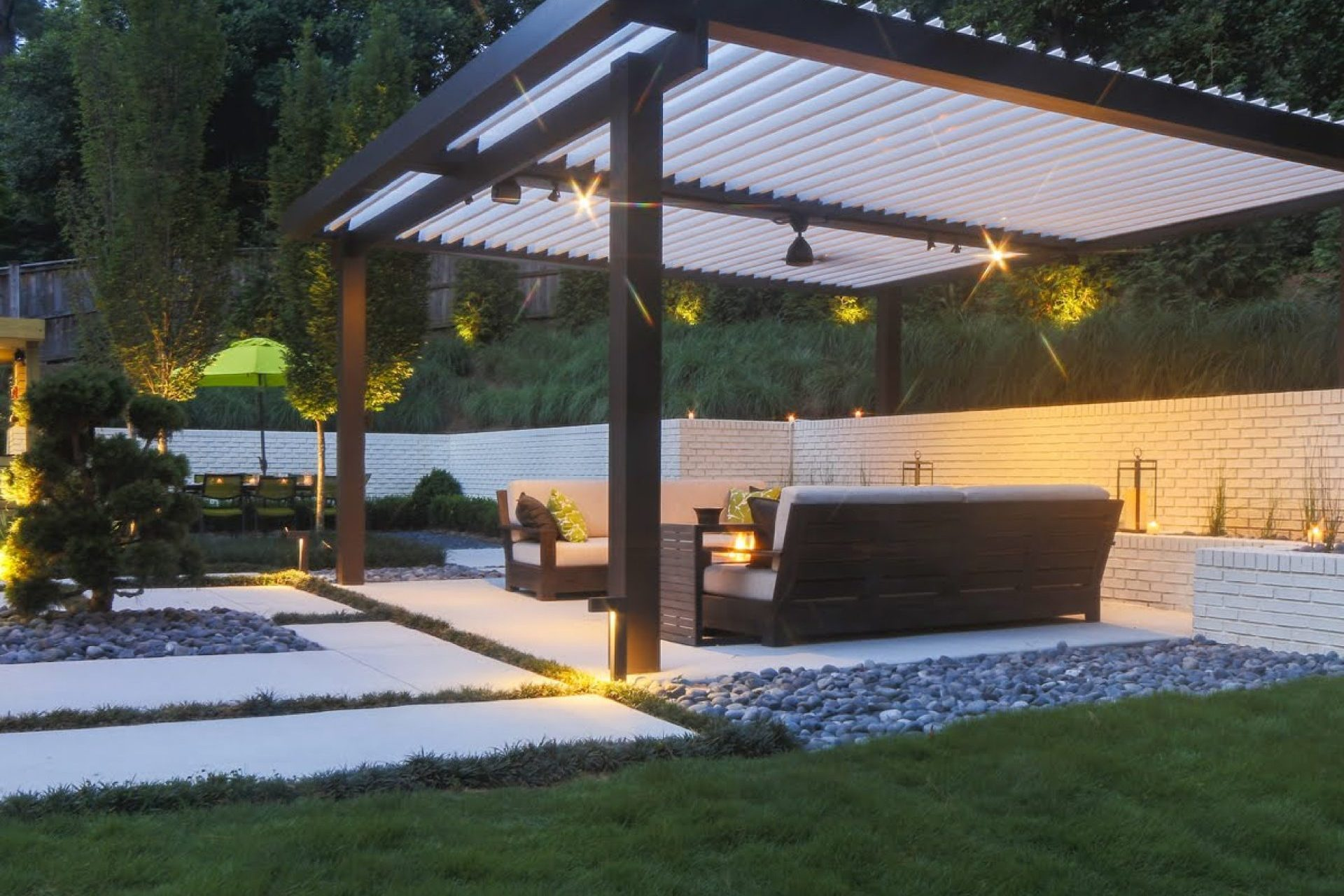 Custom louvered pergola installation by Rainier Shade — evening view with string lights