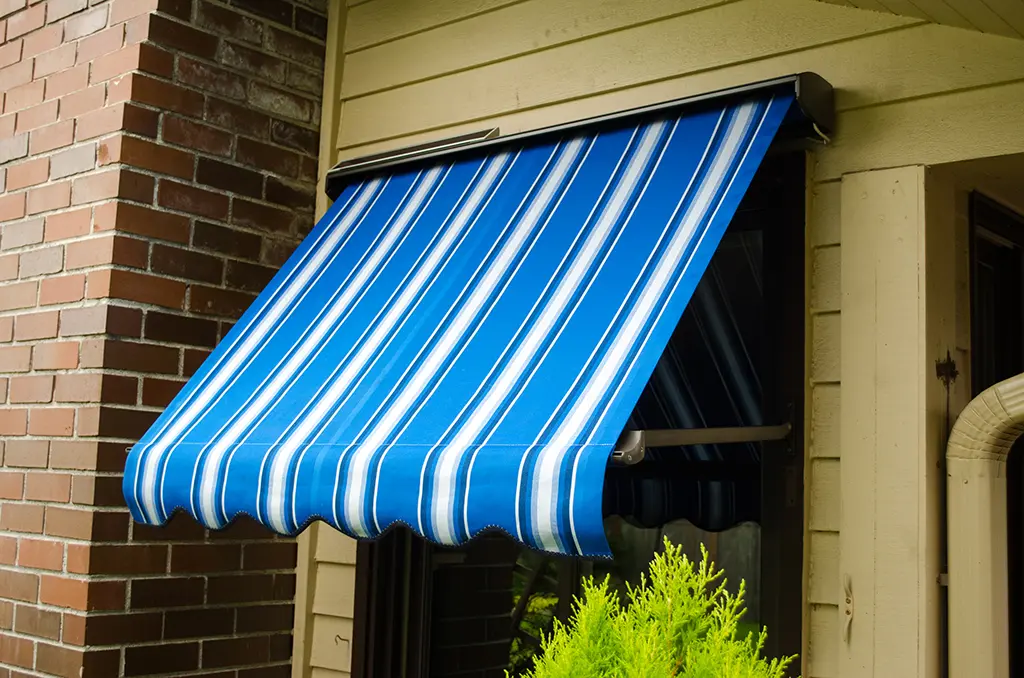 Blue striped drop arm window awning on a Seattle home