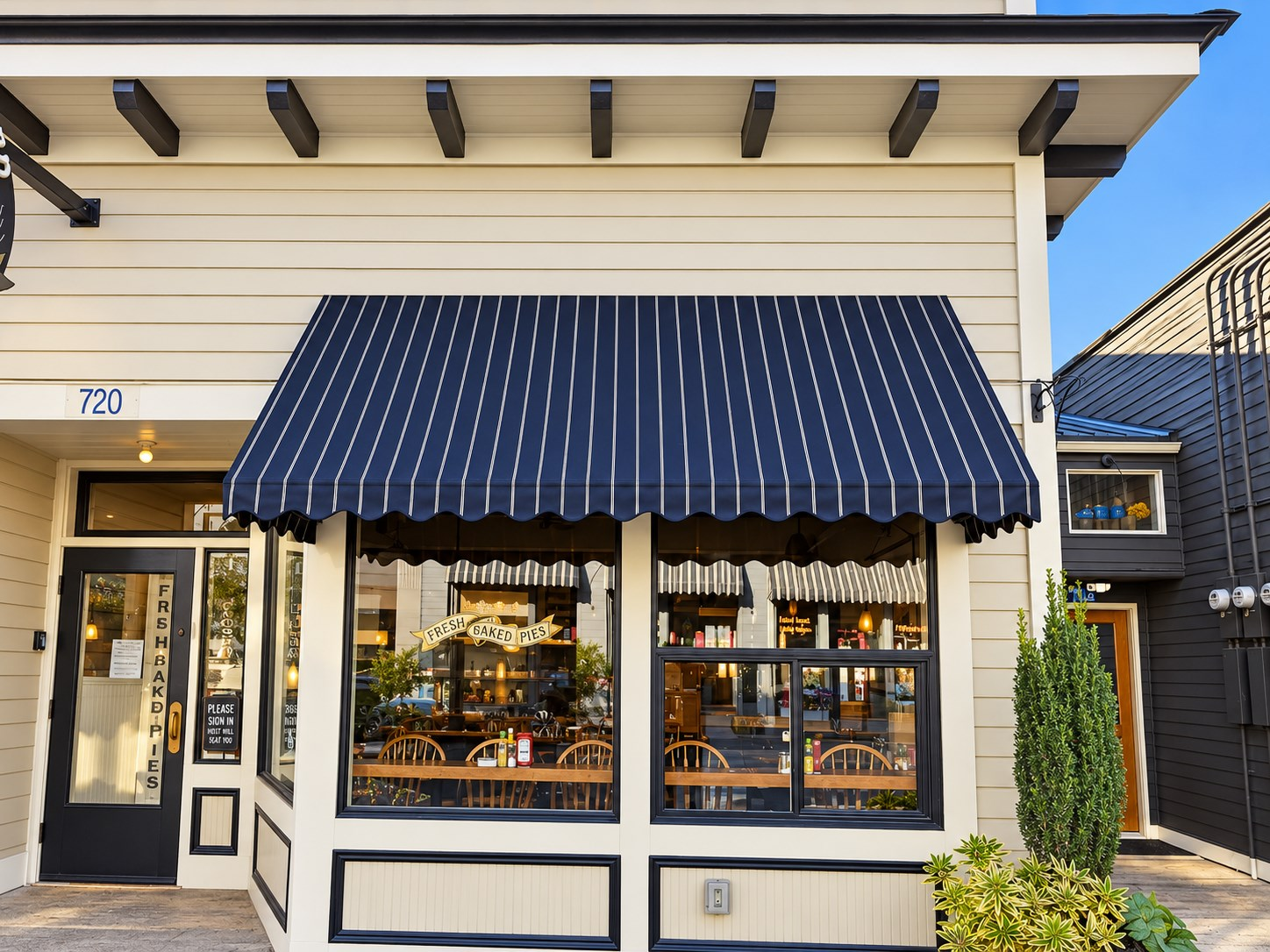 Recovered striped fabric awning with a scalloped valance on a café storefront