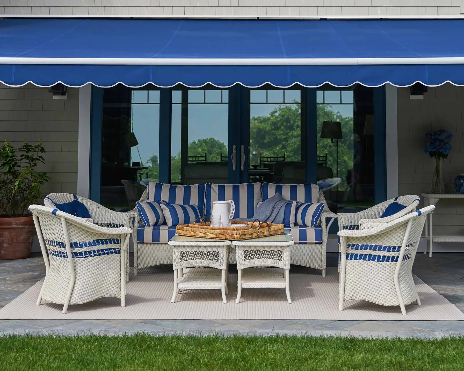 Blue Sunbrella fabric retractable awning shading a patio with outdoor furniture